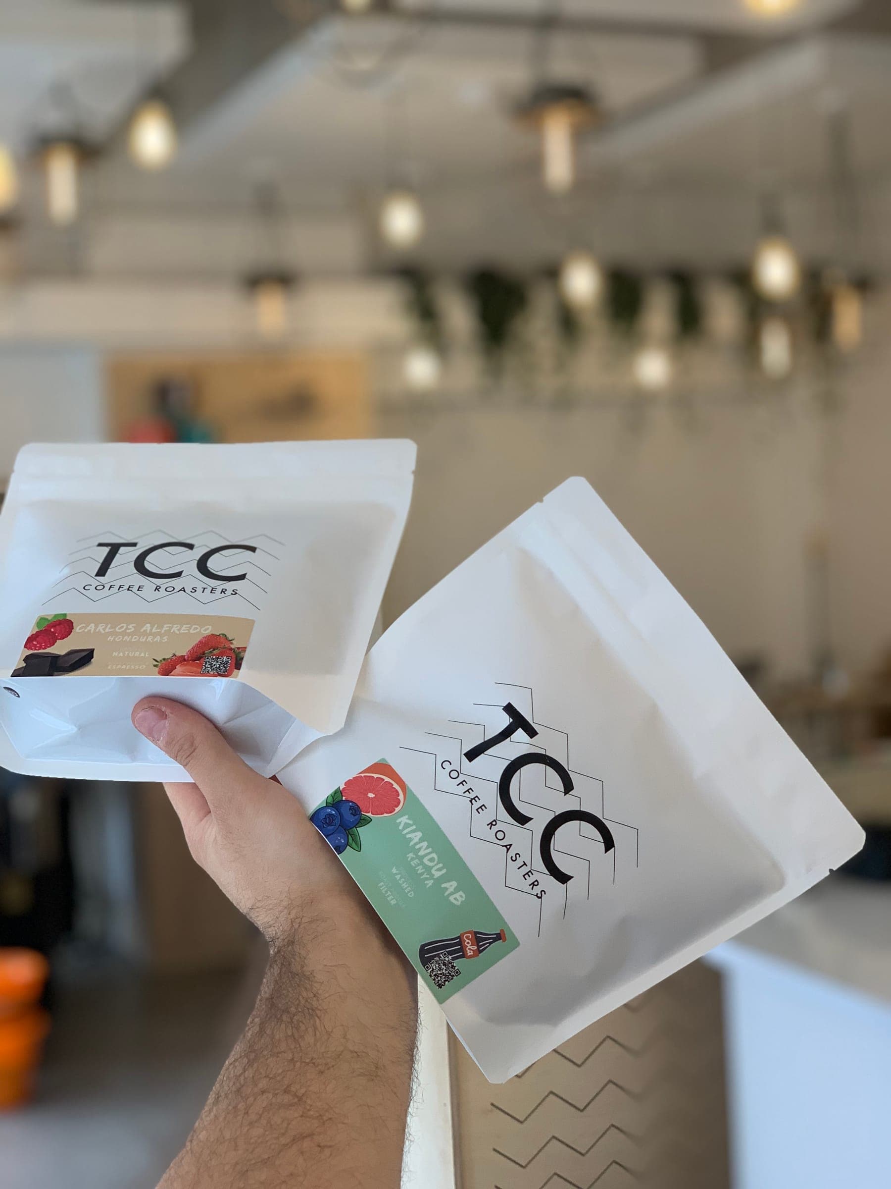 Two TCC coffee bags held up in the café